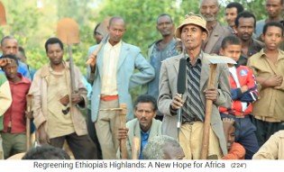 Redner mit
                          Hacken und Schaufeln an einer Dorfversammlung
                          01