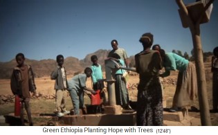 Schulkinder holen mit Giesskannen
                                Wasser an einer Handwasserpumpe