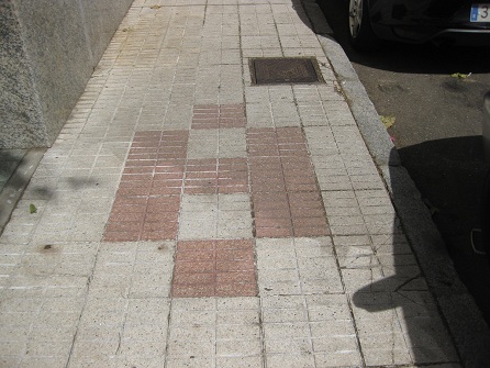 Trottoir / B�rgersteig in weissen, gerillten
                    Platten mit Mustern in roten, gerillten Platten