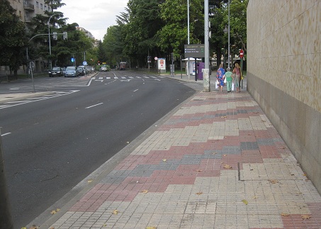 Trottoir / B�rgersteig in gerillten, weissen
                    Platten mit diagonalen B�ndern in rot-schwarz