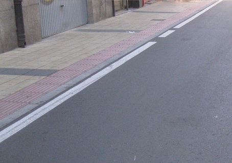 Trottoir in gelben Platten mit rotem
                            Band am Rand und schwarzen Querb�ndern