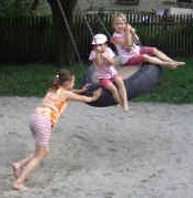 Tire swing 21 with an
                            installed wooden bottom and a swinging
                            person from outside, without location