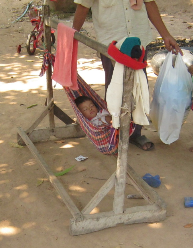 Die Babyhängematte ist auch ein
Kleiderschrank, man kann da alles möglich
dranhängen, was dem Baby gleichzeitig
Geborgenheit gibt, oder man kann die
Baby-Hängematte schmücken und ein kleines
Schloss daraus gestalten - gesehen auf einer
Reisfarm in der Region Surin, Thailand Die Babyhängematte ist auch ein
Kleiderschrank, man kann da alles möglich
dranhängen, was dem Baby gleichzeitig
Geborgenheit gibt, oder man kann die
Baby-Hängematte schmücken und ein kleines
Schloss daraus gestalten - gesehen auf einer
Reisfarm in der Region Surin, Thailand